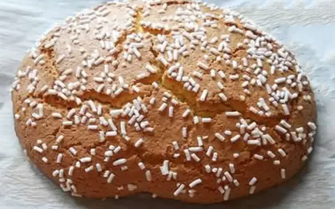 Ciambella romagnola artusi, soffice e dorata, cosparsa di zuccherini bianchi. Un dolce che sa di casa e tradizione.