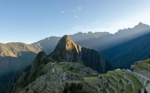 Machu Picchu i Peru, med solstrålar som bryter igenom molnen. En resa hit kan kräva vaccination Peru.