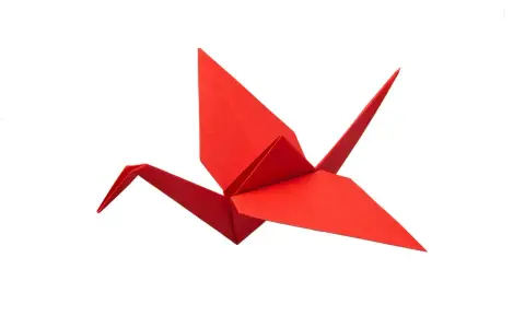 Ein roter Papierkranich, kunstvoll gefaltet als Origami.