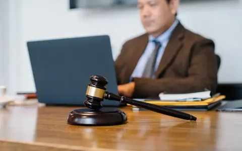 Sądowy młotek na biurku, prawnik pracuje przy laptopie. Dyskrecja w ujawnieniu informacji o zadłużeniu osobom trzecim.