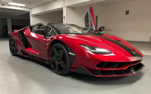 Czerwony kabriolet Lamborghini Centenario z otwartymi drzwiami typu nożycowego.
