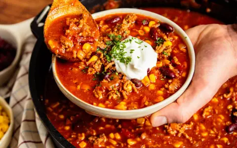 Herzhaftes Chili con Carne aus dem Dutch Oven, serviert mit einem Klecks Sour Cream und frischer Petersilie.