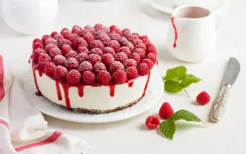 Himbeertorte mit Mascarpone, üppig belegt mit frischen Himbeeren und rotem Fruchtsirup, der über den Rand tropft.