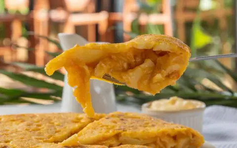 Un tenedor levanta un trozo jugoso de tortilla de espaguetis, mostrando su interior dorado y tierno.