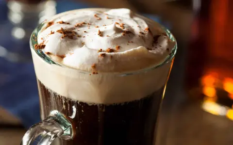 Aksamitna pianka i ciemny napój w szklance, posypane kakao. Idealna kawa z alkoholem na chłodne wieczory.