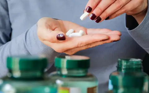 Frau nimmt Pillen, darunter 5-HTP, aus ihrer Hand.