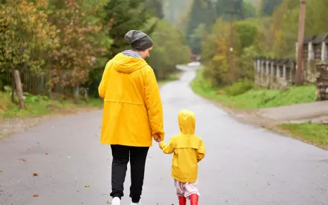 Mama i dziecko w żółtych płaszczach idą drogą. Nawet w deszczową pogodę Jastrzębia Góra oferuje atrakcje na niepogodę, jak wspólne spacery.
