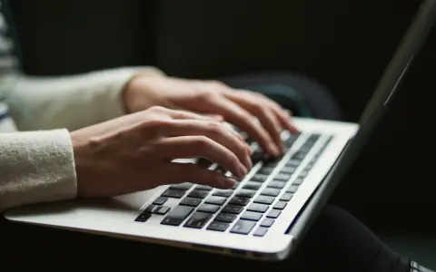 Dłonie piszą na klawiaturze laptopa, czy przed tym stawiamy przecinek? Praca zdalna w pełnym skupieniu.
