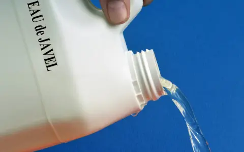 Maintenant, quelle dilution eau de javel pour nettoyer façade ? Un bidon blanc étiqueté "EAU de JAVEL" verse un liquide clair sur fond bleu.