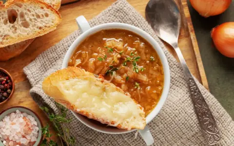 Une délicieuse recette de soupe à l'oignon, gratinée avec du fromage fondant sur une tranche de pain croustillant.