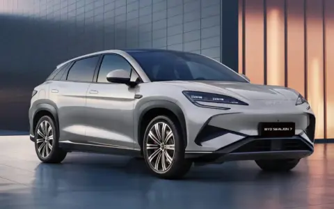 Srebrny SUV BYD Sealion 7 z nowoczesnym designem, zaparkowany przed budynkiem.