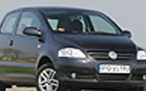 Czarny VW Fox z polskimi tablicami rejestracyjnymi stoi na tle zieleni.
