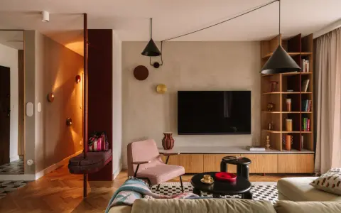 Nowoczesny salon z elementami boho. Wygodna kanapa, różowy fotel, czarne stoliki i regał. W przedpokoju ławka i lustro. Idealne miejsce na relaks po całym dniu. Ten **kosztorys remontu** był wart każdej złotówki.