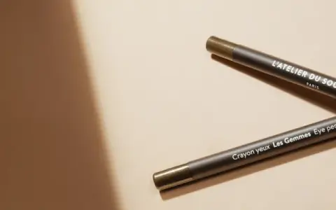 Deux crayons pour les yeux L'Atelier du Sourcil, un avant et un après, sur fond beige.