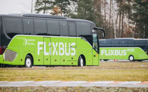 Zielony autobus Flixbus z napisem "Akademia Kierowcy" stoi na trawie. Czyżby kolejne flixbus opóźnienia?