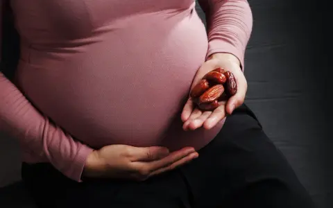 Kobieta w ciąży trzyma w dłoni garść daktyli. To naturalny sposób na wsparcie organizmu w tym wyjątkowym czasie.