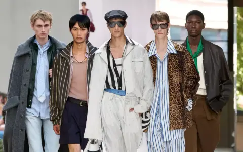 Five models showcase bold gay men fashion on a runway, featuring a mix of stripes, leopard print, and stylish outerwear.
