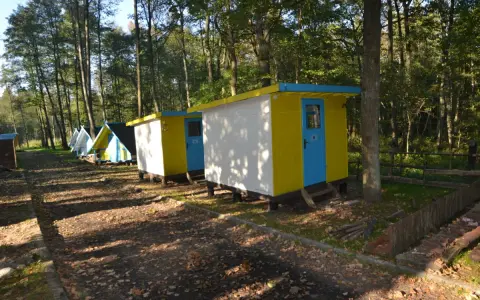 Kolorowe domki kempingowe w lesie, jak małe perły Krutyni, czekają na gości.