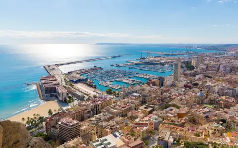 Widok na port jachtowy i plażę w słoneczny dzień. Tak właśnie wygląda Alicante, gdzie jest to piękne miasto.