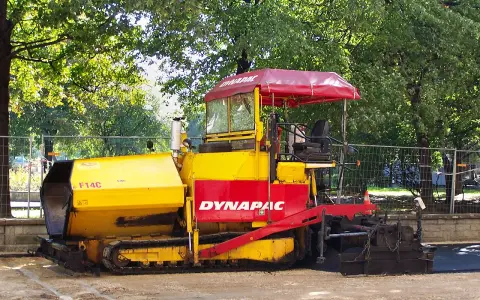 Żółto-czerwony rozściełacz do kruszywa Dynapac F14C na placu budowy.