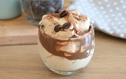 Deliziosa crema al caffè veloce in un bicchiere, guarnita con chicchi di caffè e cacao.