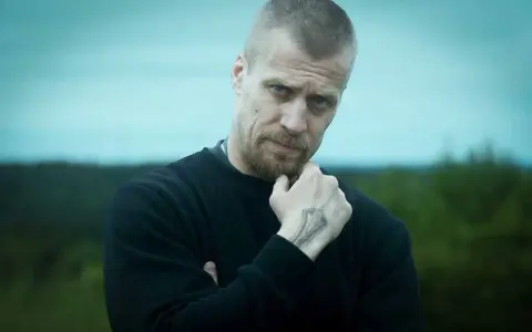 Jens Hultén, känd från filmer och tv-program, med en intensiv blick och en tatuering på handen.