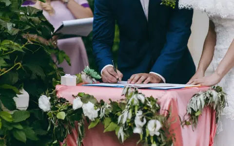Pan młody podpisuje dokumenty, a obok stoi panna młoda. Zastanawiasz się, ile kosztuje ślub cywilny?