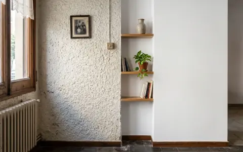 Un rincón con un radiador antiguo, un cuadro familiar y estanterías. La textura de la pared es rugosa, pero merece la pena quitar el gotelé para un acabado más liso.