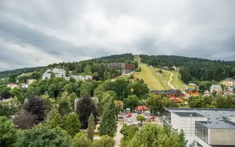 Widok na Krynicę-Zdrój z trasą narciarską i zabudowaniami. Sprawdź sanatorium krynica zdrój cennik.