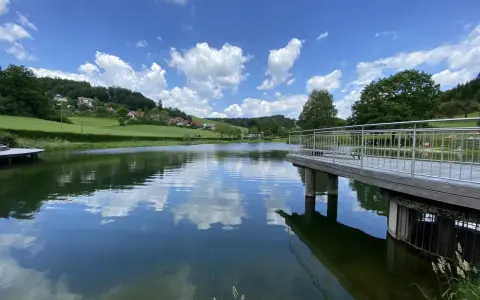 Idyllischer badesee waldhausen mit Steg und Spiegelung der Wolken im ruhigen Wasser.