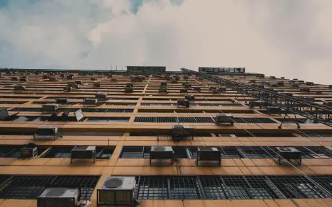 Fachada de edificio con múltiples unidades exteriores de aire acondicionado, mostrando dónde colocar la unidad exterior del aire acondicionado en cada ventana.