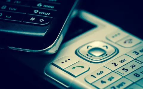 Zbliżenie na klawiatury dwóch telefonów komórkowych, jeden czarny, drugi srebrny.