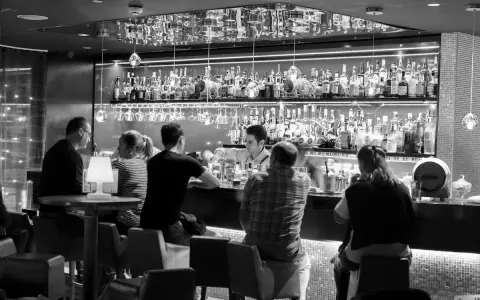 Gente en un bar cine, con un camarero sirviendo bebidas detrás de la barra llena de botellas.