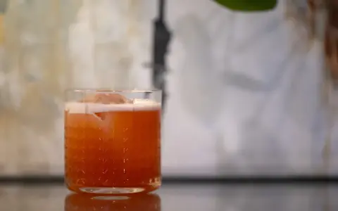 Ein erfrischender Jungle Bird Cocktail mit Eis und Schaum in einem Glas mit Rautenmuster.