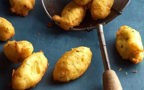 Goldbraune Dauphine Kartoffeln, frisch frittiert und auf einem Abtropfsieb. Ein Genuss für jeden Kartoffelliebhaber.