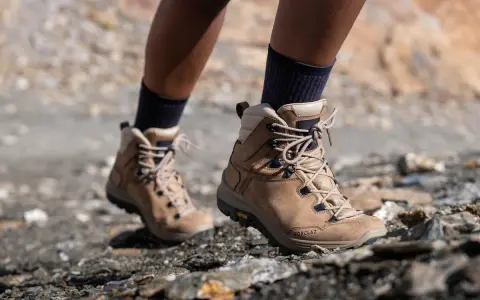 Botas de montaña Forclaz de color marrón, con cordones, sobre terreno rocoso.