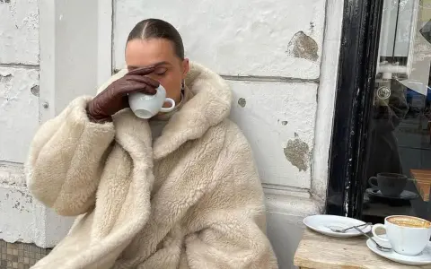 Vanilla girl w kremowym futrze pije kawę, otulona ciepłem i spokojem.