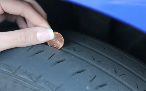 Dito si vede perché le gomme si consumano all'interno: una moneta viene inserita nel battistrada usurato di uno pneumatico.
