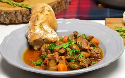 Wołowina po burgundzku z pieczarkami i marchewką, podana z chrupiącą bagietką. Aromatyczne danie, które rozpływa się w ustach.