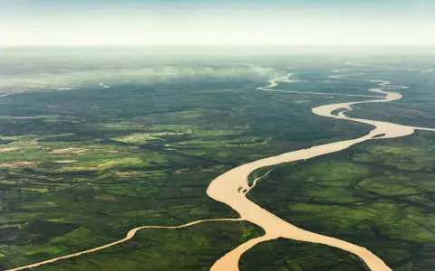 Szeroka, meandrująca amazonka rzeka przecina bujną, zieloną dżunglę, tworząc malowniczy krajobraz z lotu ptaka.