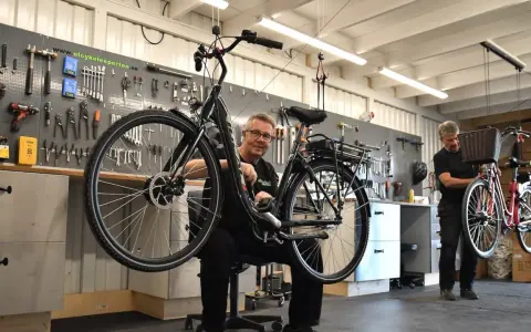 Mekaniker arbetar med en elcykel i verkstad. Verktyg på väggen visar att detta är en plats för bidrag till elcykel.