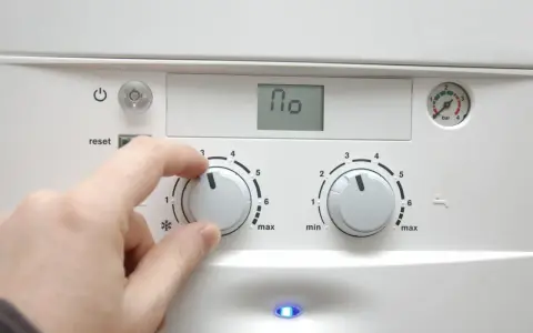 Dłoń reguluje pokrętłem pieca, przygotowując dom na nadchodzący sezon grzewczy. Na wyświetlaczu widnieje "110".