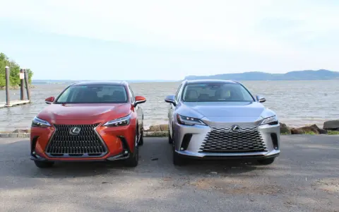 Dwa lśniące suvy Lexus stoją obok siebie nad wodą.