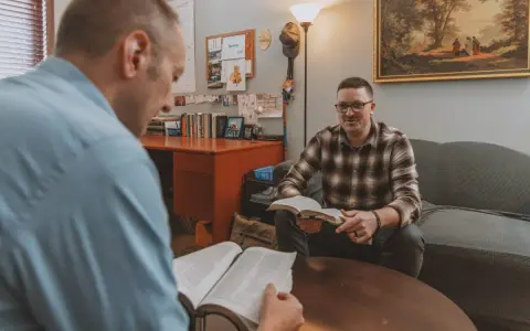 Two men discuss the Bible, exploring why God sent Jesus to save humanity.