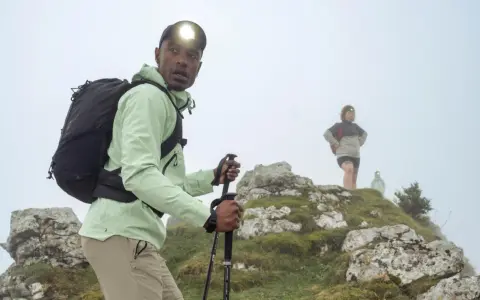 Randonneur ajustant son réglage bâton de marche, prêt à affronter la brume avec sa lampe frontale.