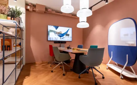 Aménagement de locaux professionnels : salle de réunion moderne avec table, chaises colorées, écran et tableau blanc mobile.