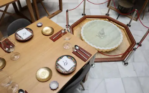 Mesa elegante en el restaurante El Puente El Tejar, con vajilla dorada y una fuente ornamental en el centro.