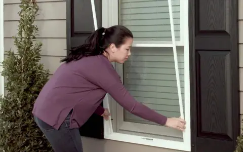 Woman demonstrates how to replace screen door mesh on a window.