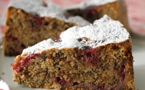 Ein saftiges Stück Buchweizentorte mit Preiselbeeren, bestäubt mit Puderzucker.