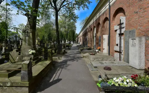 Aleja przez zabytkową nekropolię z nagrobkami i mauzoleami wzdłuż ceglanego muru z arkadami.